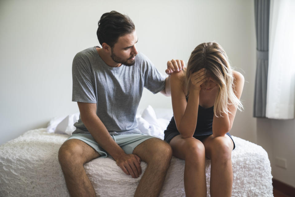 guy trying to comfort a woman sitting on the bed