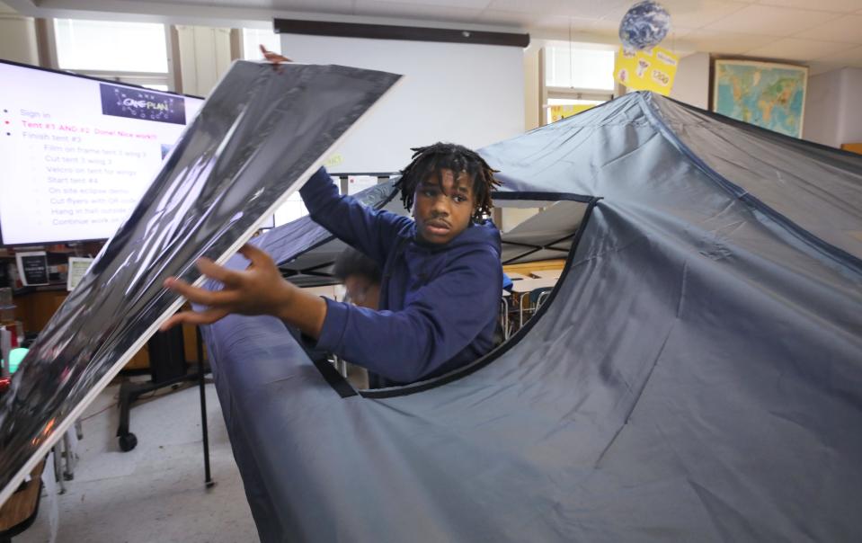 Avon Payne, a junior, and Kayden Svkapi, tenth grade, lift into place a silver black polymer solar film covered skylight into a hole cut into a tent canopy in science teacher Ellen Post's classroom at Wilson High School in Rochester Thursday, March 14, 2024. The tent canopies with their special skylights will be used to view the upcoming total solar eclipse on April 8, 2024.