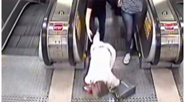 A woman distracted by her phone falls over at the top of an escalator. Source: 7 News