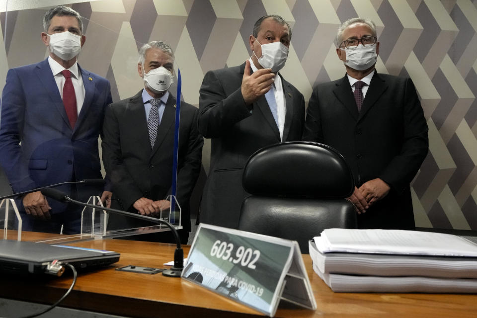 Senators Omar Aziz, second from right, and Renan Calheiros, right, speak behind a desk with a plaque showing the number of COVIVD-19 deaths in Brazil at the start of a session by a commission investigating the government’s management of the COVID-19 pandemic at the Federal Senate in Brasilia, Brazil, Wednesday, Oct. 20, 2021. Calheiros formally presented his report recommending President Jair Bolsonaro be indicted on criminal charges for allegedly bungling Brazil’s response to pandemic and pushing the country’s death toll to second-highest in the world. Senator Humberto Costa stands second from left, and Senator Rogerio Carvalho stands at far left. (AP Photo/Eraldo Peres)