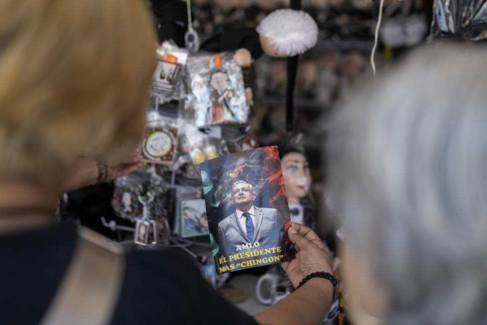 ARCHIVO - Una compradora sostiene una postal del presidente mexicano, Andrés Manuel López Obrador, que dice, "AMLO, el presidente más chingón", que se vende afuera del Palacio Nacional de Ciudad de México, el 14 de marzo de 2024. (AP Foto/Eduardo Verdugo, Archivo)