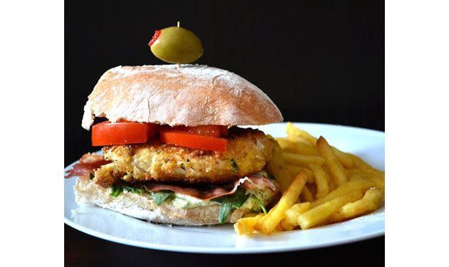 <p>Ce burger regorge de saveurs classiques italiennes. Prenez deux filets de poulet (pour quatre personnes) et coupez-les en deux. Déposez les filets de poulet sur une feuille de film alimentaire et recouvrez-les d’une autre feuille. Aplatissez les filets à l’aide d’un rouleau à pâtisserie. Trempez chaque filet dans un bol contenant un œuf battu, et faites-les cuire quelques minutes de chaque côté jusqu’à ce qu’ils soient croustillants. Pendant ce temps, mélangez une cuillère à café de jus de citron, 3 cuillères à café de pesto frais et 2 cuillères à soupe de mayonnaise. Étalez le mélange sur une moitié d’un pain ciabatta puis placez le poulet, du prosciutto grillé, des feuilles de roquette et de la tomate. Servez-les avec un cure-dent surmonté d’une olive.</p>