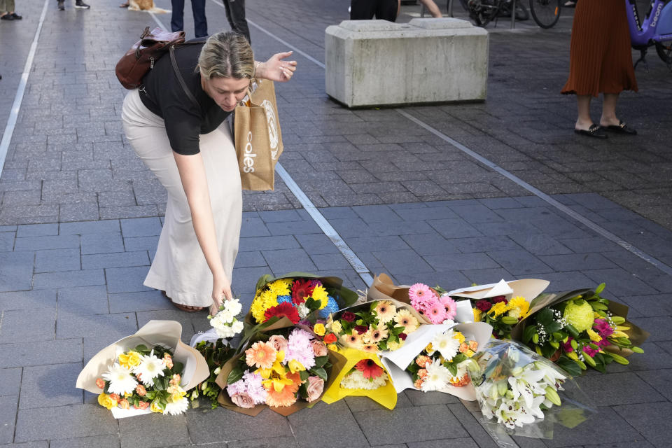 A woman brings flowers to an impromptu memorial at Bondi Junction in Sydney, Sunday, April 14, 2024, after several people were stabbed to death at a shopping center Saturday. (AP Photo/Rick Rycroft)