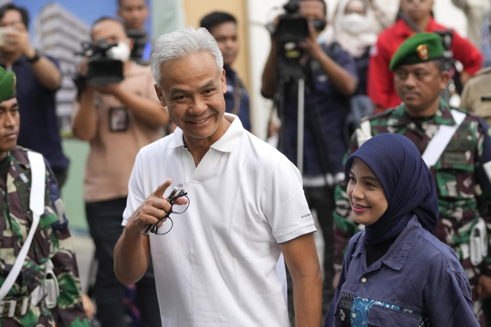 Presidential candidate Ganjar Pranowo, left, gestures at reporters as he walks with his wife Siti Atikoh upon arrival for the medical check up required for his candidacy in the upcoming presidential election, at Gatot Subroto Army Hospital in Jakarta, Indonesia, Sunday, Oct. 22, 2023. The world's third-largest democracy is holding its legislative and presidential elections on Feb. 14, 2024. (AP Photo/Dita Alangkara)