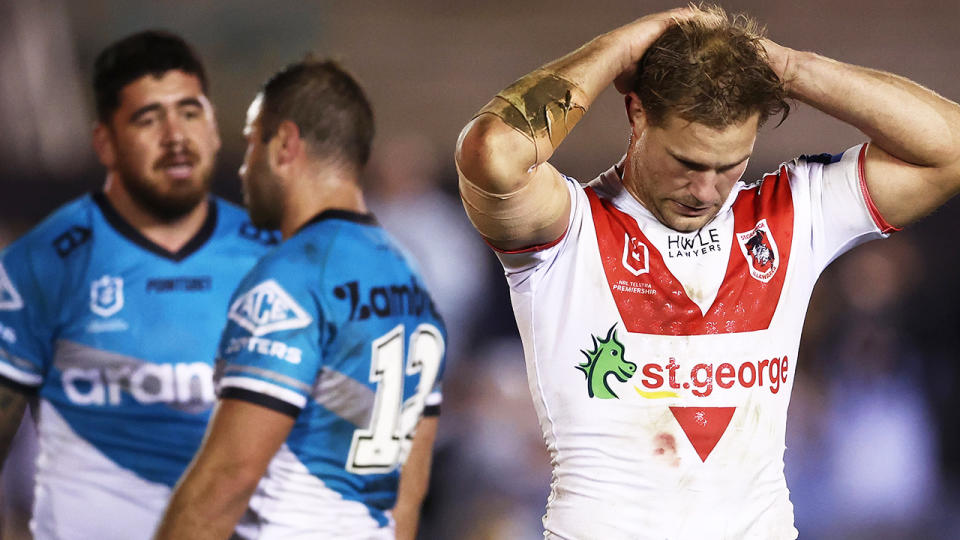 Jack de Belin has his hands on his head as two Cronulla players celebrate in the background.