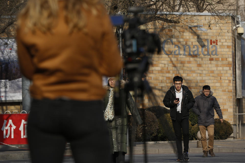 A journalist film people walk by the Canadian Embassy in Beijing, Friday, Dec. 14, 2018. Canada is being battered by diplomatic ill winds. First, President Donald Trump attacked Canada on trade. Then Saudi Arabia punished it for speaking up for human rights. Now China has the country in its cross-hairs, detaining two Canadians in apparent retaliation for the arrest of a top Chinese tech executive on behalf of the U.S. Canada's normally reliable ally to the south has left it high and dry. (AP Photo/Andy Wong)