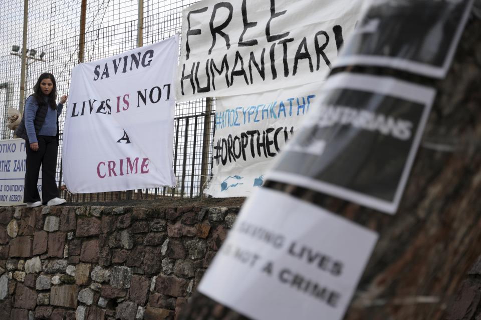 A protester hangs a banner outside a court in Mytilene, on the northeastern Aegean island of Lesbos, Greece, Friday, Jan. 13, 2023. The trial of 24 Greek and foreign aid workers and volunteers who participated in migrant rescue operations has resumed on an eastern Greek island, in a prosecution that has drawn widespread criticism from international human rights groups. (AP Photo/Panagiotis Balaskas)