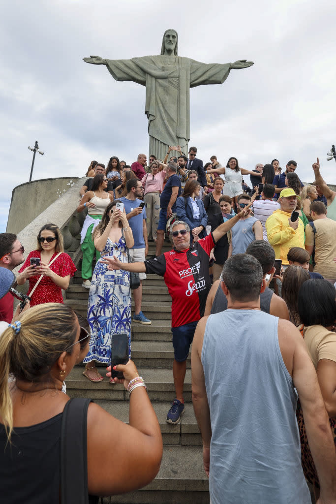 Tourists gather at the base of Christ the Redeemer statue in Rio de Janeiro, taking photos and enjoying the view