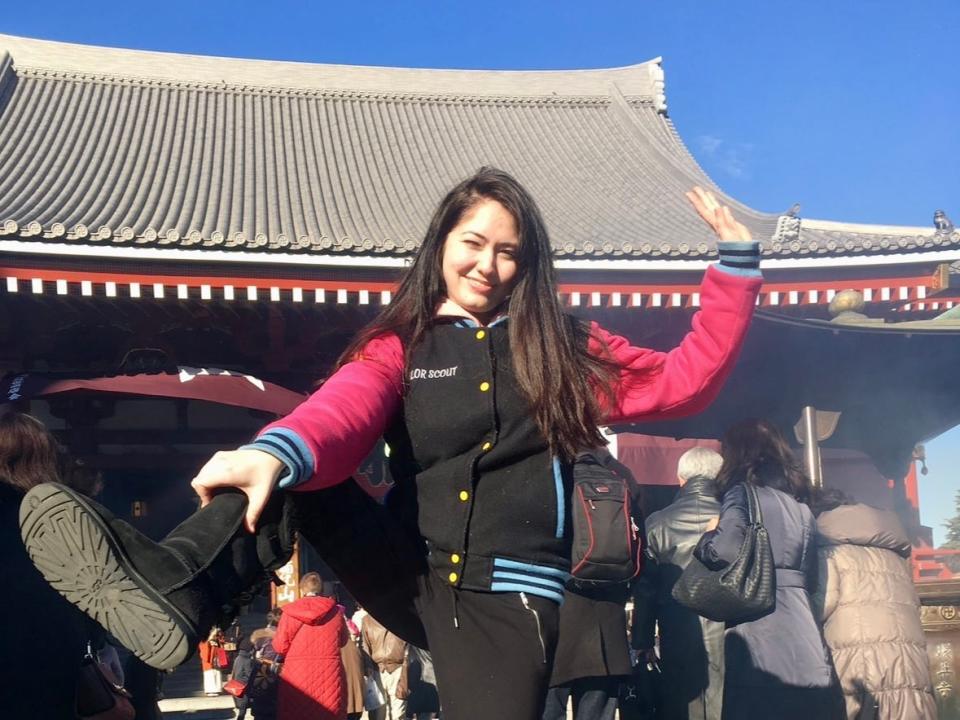 Girl lifting her leg outside Japanese temple