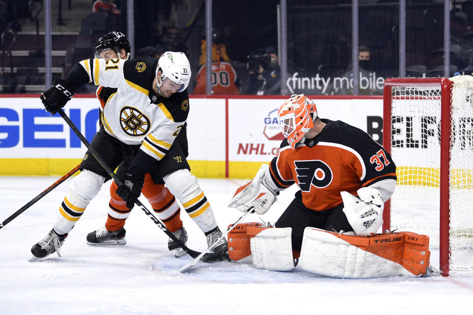 Philadelphia Flyers goaltender Brian Elliott, right, makes a save on a shot attempt by Boston Bruins' Nick Ritchie as Flyers' Robert Hagg, rear, defends during the second period of an NHL hockey game, Saturday, April 10, 2021, in Philadelphia. (AP Photo/Derik Hamilton)