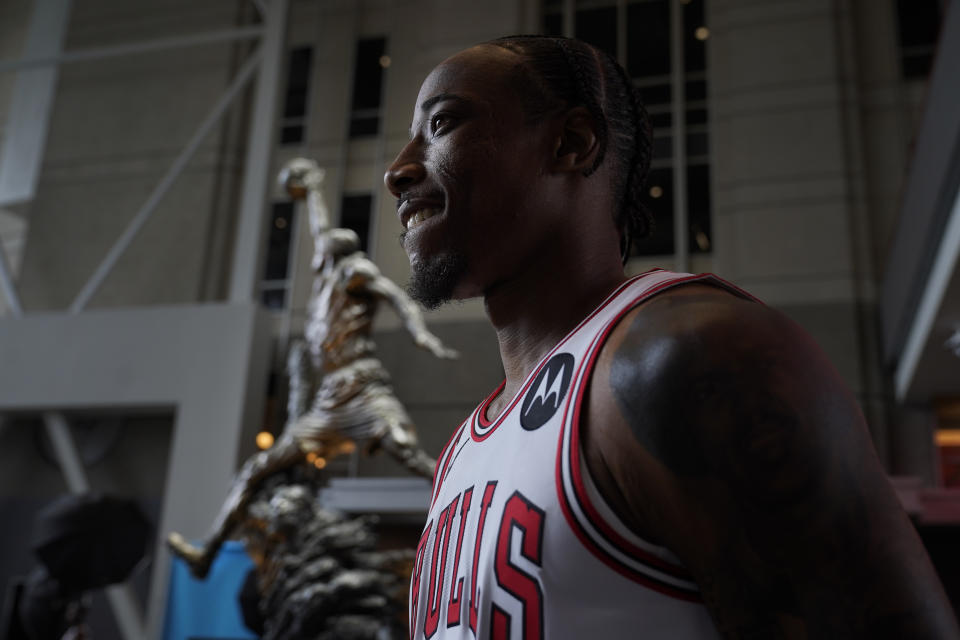 Chicago Bulls' DeMar DeRozan stands near the Michael Jordan statue as he watches a teammate getting photographed during the Bulls NBA basketball media day Monday, Sept. 26, 2022, in Chicago. (AP Photo/Charles Rex Arbogast)