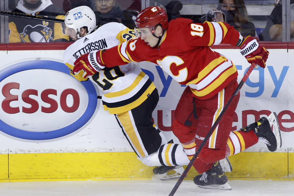 Pittsburgh Penguins' Marcus Pettersson, left, of Sweden, is knocked down by Calgary Flames' Tyler Pitlick during the first period of an NHL hockey game, Monday, Nov. 29, 2021 in Calgary, Alberta. (Larry MacDougal/The Canadian Press via AP)