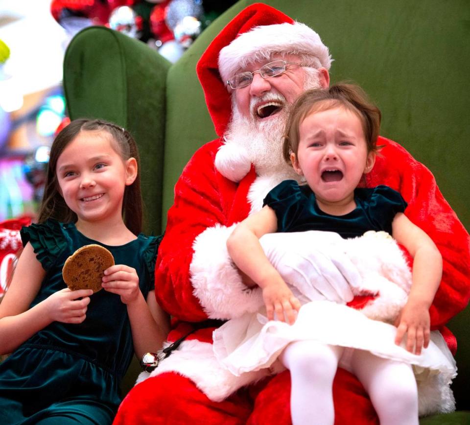 Alana Bushong, 2, of Joint Base Lewis-McChord, expresses her displeasure as she poses for photos with Santa and her sister, LeeLynn Bushong, 6, at the South Hill Mall in Puyallup, Washington, on Wednesday, Nov. 24, 2021.