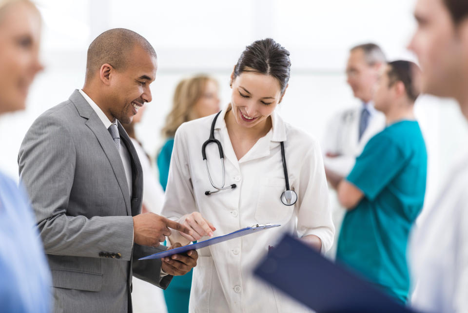 A doctor looking at a tablet with another person.