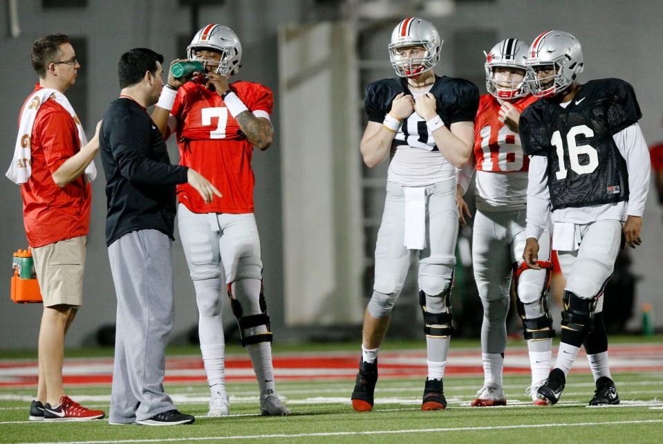 Ohio State quarterbacks Dwayne Haskins (7), Joe Burrow (10), Tate Martell (18), and J.T. Barrett listen as assistant coach Ryan Day gives instructions during a practice in 2017.