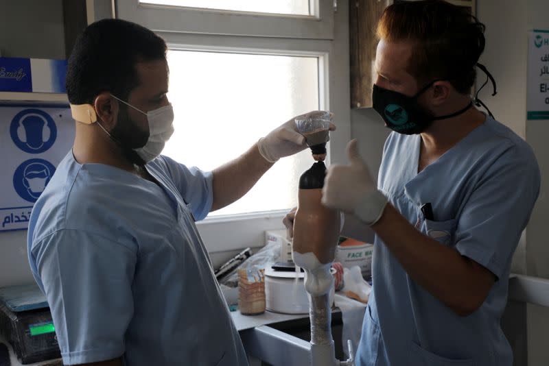 Abdelmawla Ibrahim, a Syrian amputee and physical therapist, works with a colleague on a prosthetic at Al-Bab centre for prosthetics in Al-Bab