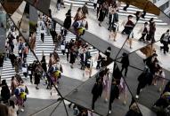 Passersby wearing protective face masks, following an outbreak of the coronavirus disease (COVID-19), are reflected in mirrors at a shopping center in Tokyo