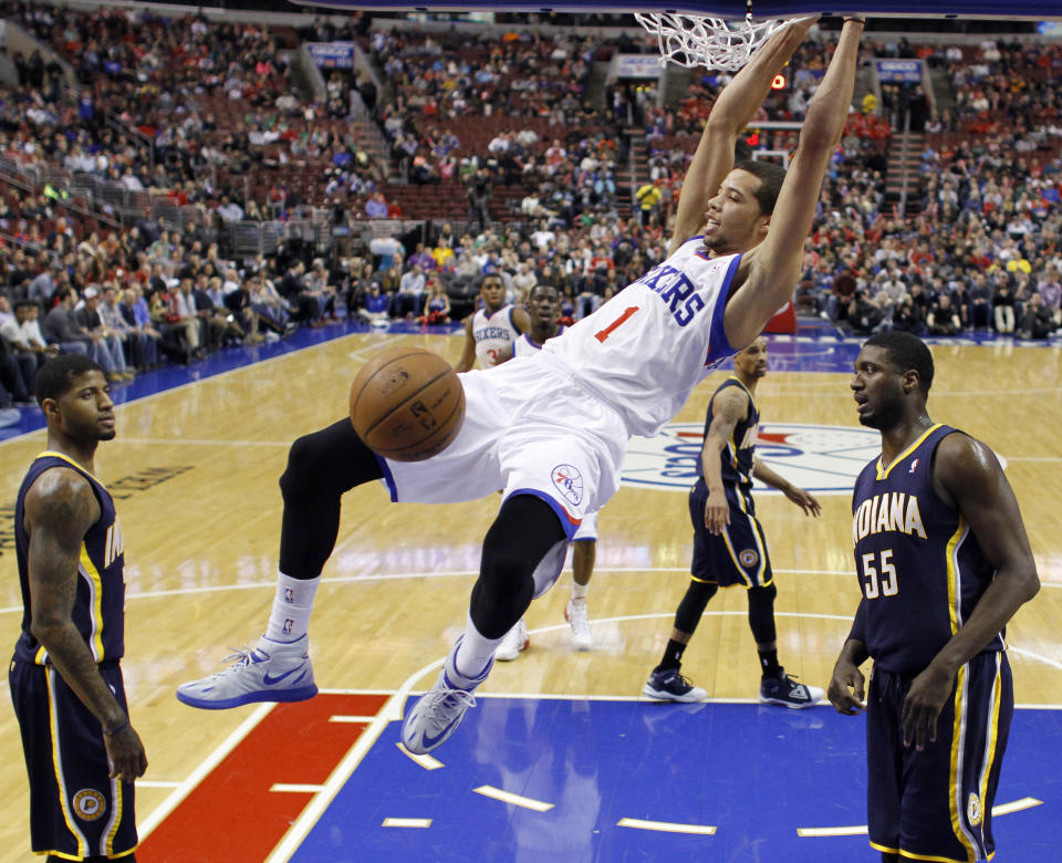 Philadelphia 76ers' Michael Carter-Williams, center, hangs on the rim after a dunk as Indiana Pacers' Paul George, left, and Roy Hibbert look on during the first half of an NBA basketball game on Friday, March 14, 2014, in Philadelphia. (AP Photo/Matt Slocum)