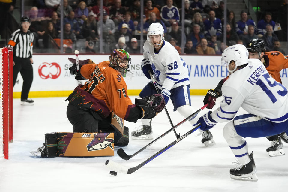 Toronto Maple Leafs center Alexander Kerfoot (15) shoots the puck past Arizona Coyotes goaltender Karel Vejmelka (70) for a goal as Coyotes defenseman Shayne Gostisbehere (14) is unable to help and Maple Leafs left wing Michael Bunting (58) looks on during the second period of an NHL hockey game in Tempe, Ariz., Thursday, Dec. 29, 2022. (AP Photo/Ross D. Franklin)