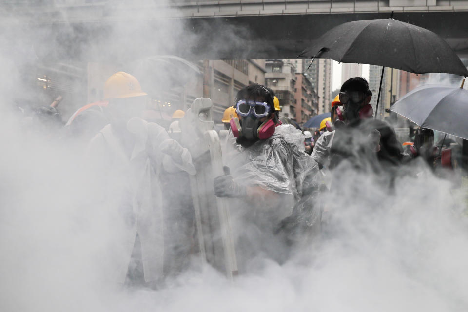 Demonstrators scramble during a protest in Hong Kong, Sunday, Aug. 25, 2019. Police in Hong Kong used tear gas Sunday to clear pro-democracy demonstrators who had taken over a street and brought out water cannon trucks for the first time in the summer long protests. (AP Photo/Kin Cheung)