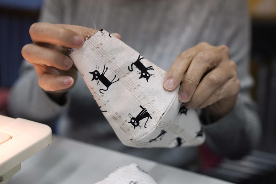 In this Monday, Feb. 17, 2020, photo, a volunteer makes a handmade cotton mask in Hong Kong. Volunteers from a Hong Kong theater group are turning their backstage skills to helping out against the new coronavirus, sewing reusable protective masks for those who can't access or afford them. Jo Ngai, a drama lover and founder of the Nonsensemakers, along with her friend Jessie Han, have turned a theater rehearsal room into a temporary handmade mask factory. (AP Photo/Kin Cheung)