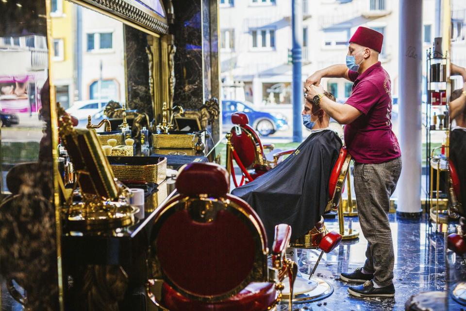 Muhammet 'Memo' Akbas cuts Aleksandar Petrovic's hair in a barber shop in Freiburg, Germany, Monday, March 1, 2021. Hairdressers across Germany are reopening for business after a two and a half month closure, another cautious step as the country balances a desire to loosen restrictions with concern about the impact of more contagious coronavirus variants. (Philipp von Ditfurth/dpa via AP)