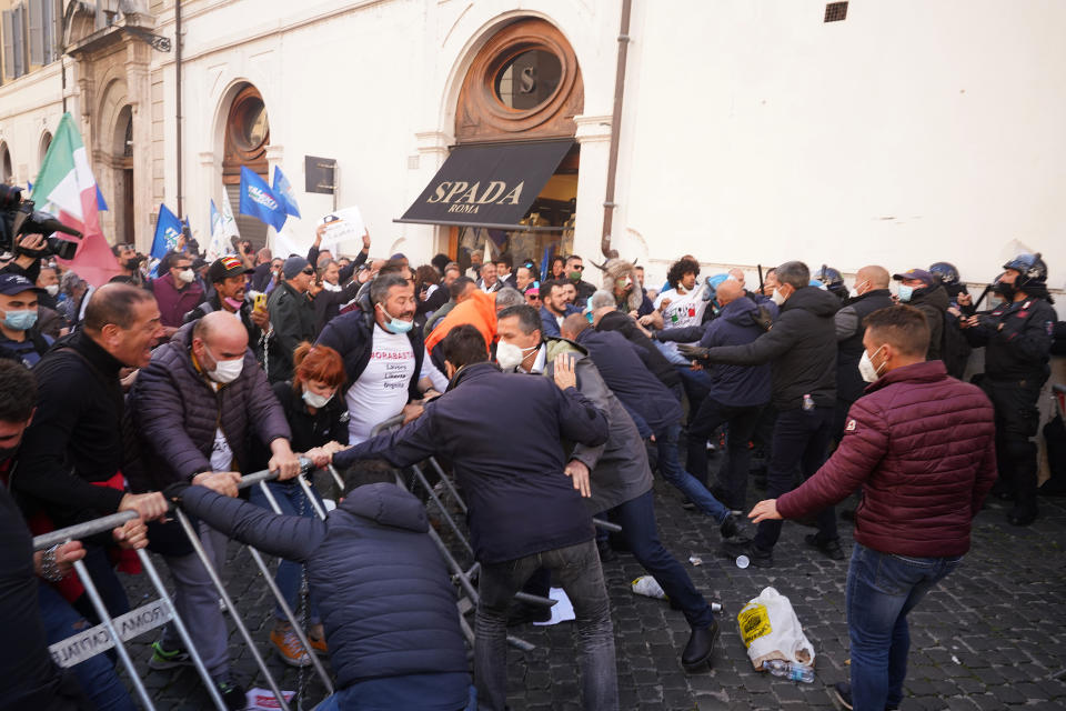 Demonstrators scuffle with Italian Policemen during a protest by Restaurant and shop owners outside the Lower Chamber in Rome, Tuesday, April 6, 2021. Demonstrators demanded to reopen their business and protested against restrictive measures by the Italian Government to cope with the surge of COVID-19 cases. (AP Photo/Andrew Medichini)