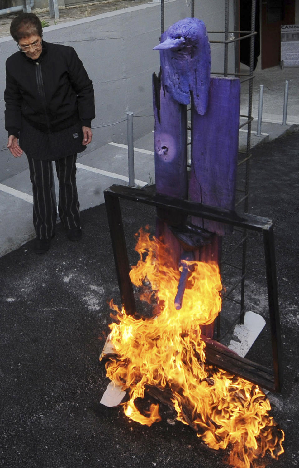 Italian artist Rosaria Matarese looks at one of her creations as it burns in front of the Casoria Contemporary Art Museum, near Naples, Wednesday, April 18, 2012. This is the second creation Antonio Manfredi, the director of the museum, burnt, the day before he burned a painting by a French artist, to protest shortage of funds. Manfredi threatened to burn paintings if financial aid wasn't promised. Italy's museums have been chronically short of funds for decades, but art world officials say the economic crisis has aggravated their pligh. (AP Photo/Franco Castano)