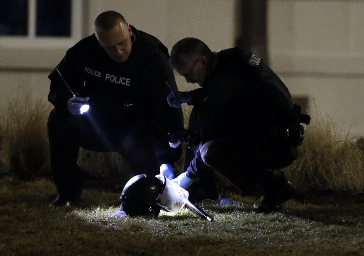 Police shine a light on a helmet as they investigate the scene where two officers were shot outside the Ferguson Police Department on March 12. (AP/Jeff Roberson)