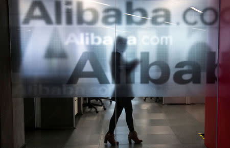 FILE PHOTO: An employee is seen behind a glass wall with the logo of Alibaba at the company's headquarters on the outskirts of Hangzhou, Zhejiang province, April 23, 2014. REUTERS/Chance Chan/File Photo