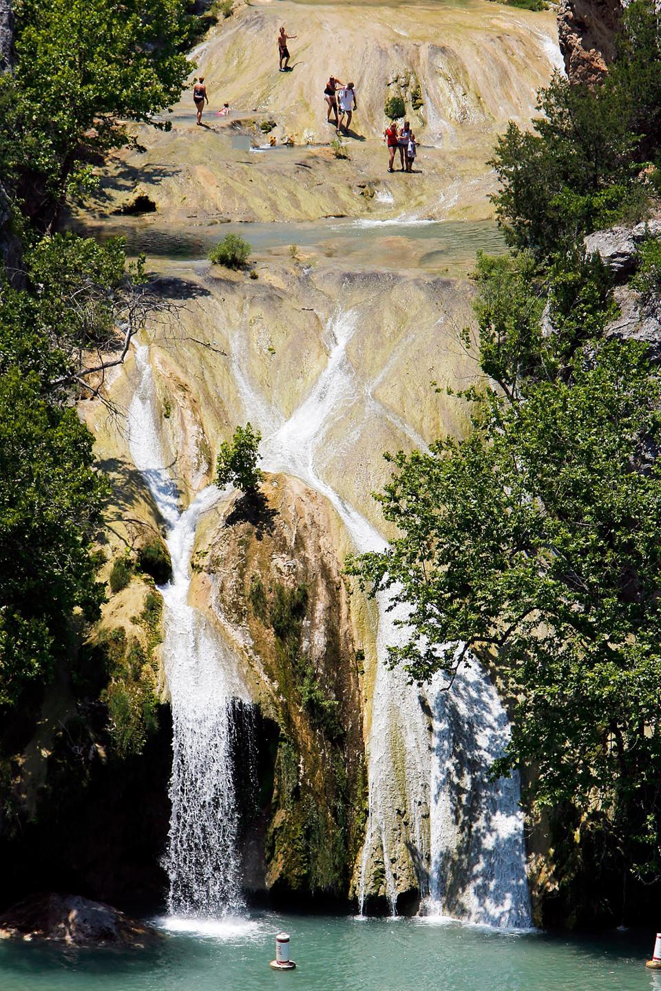 Visitors to Turner Falls swim and walk at the upper falls.