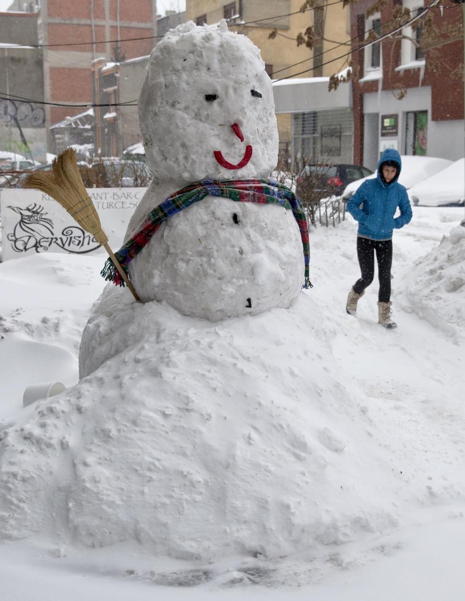 A woman walks by a large snowman in Bucharest, Romania, Wednesday, Jan. 29, 2014. Weather forecasters issued a code red severe weather warning as a second wave of blizzards affects the southeastern regions of Romania disrupting road and rail traffic.(AP Photo/Vadim Ghirda)