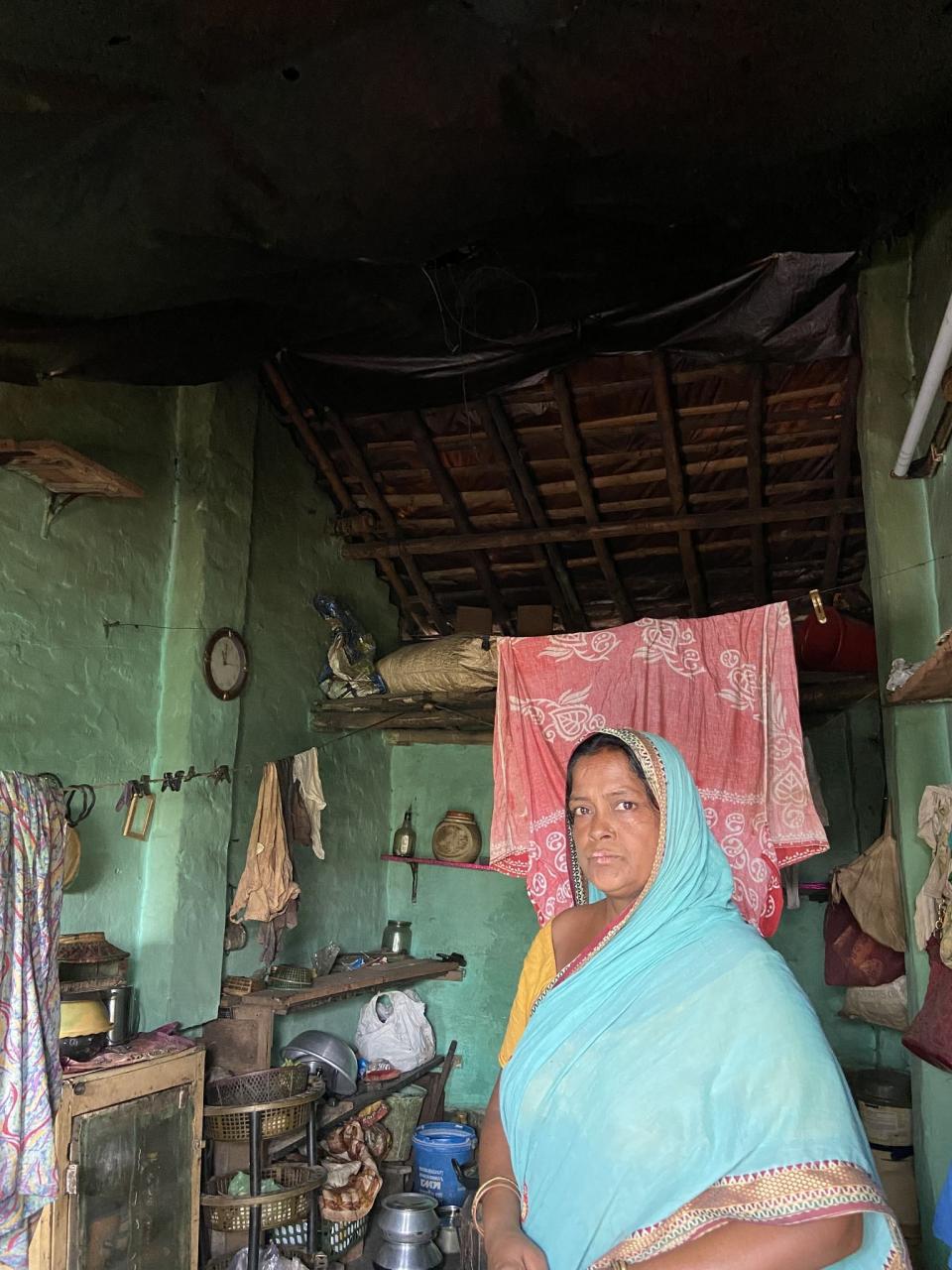 One of the victims uses plastic sheets to cover her damaged roof.