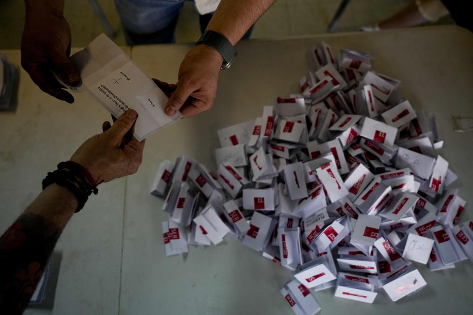 Trabajadores electorales abren los votos para el conteo tras el cierre de urnas en Santiago, Chile, el domingo 17 de diciembre de 2023. Por segunda vez, los chilenos van a un referéndum para decidir si reemplazan la constitución vigente, heredada de la dictadura de Augusto Pinochet, por un nuevo texto. (AP Foto/Esteban Félix)