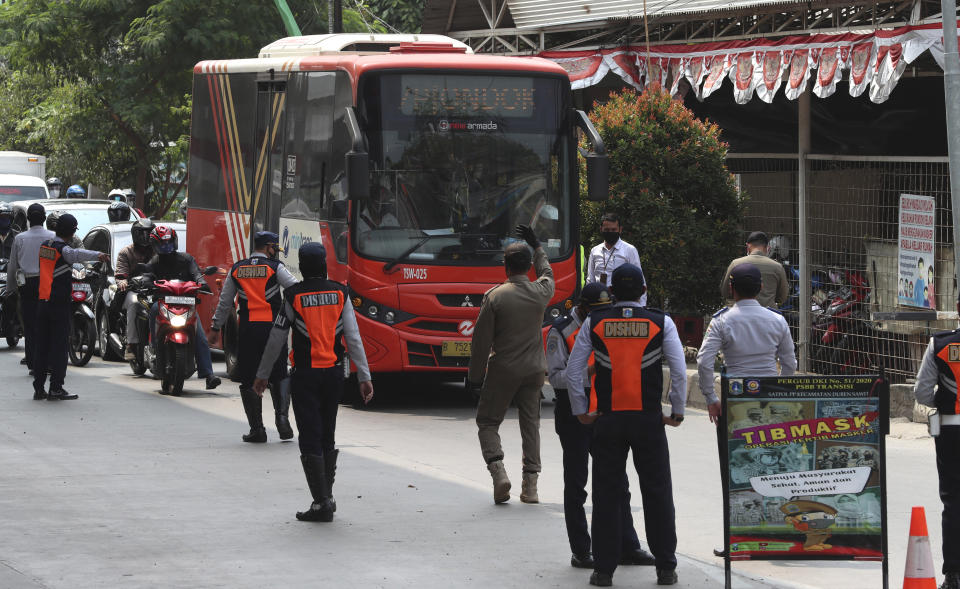 Officers stand guard at a police check point during the imposition of large-scale restriction to curb the spread of the coronavirus outbreak in Jakarta, Indonesia, Monday, Sept. 14, 2020. Indonesia's capital on Monday begins to reimpose large-scale social restrictions to control a rapid expansion in the virus cases. (AP Photo/Achmad Ibrahim)