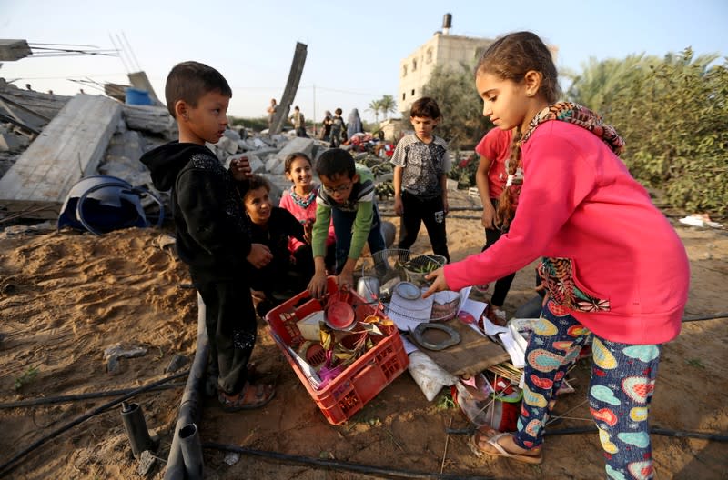 Palestinian children collect objects from a house destroyed in an Israeli air strike in the southern Gaza Strip