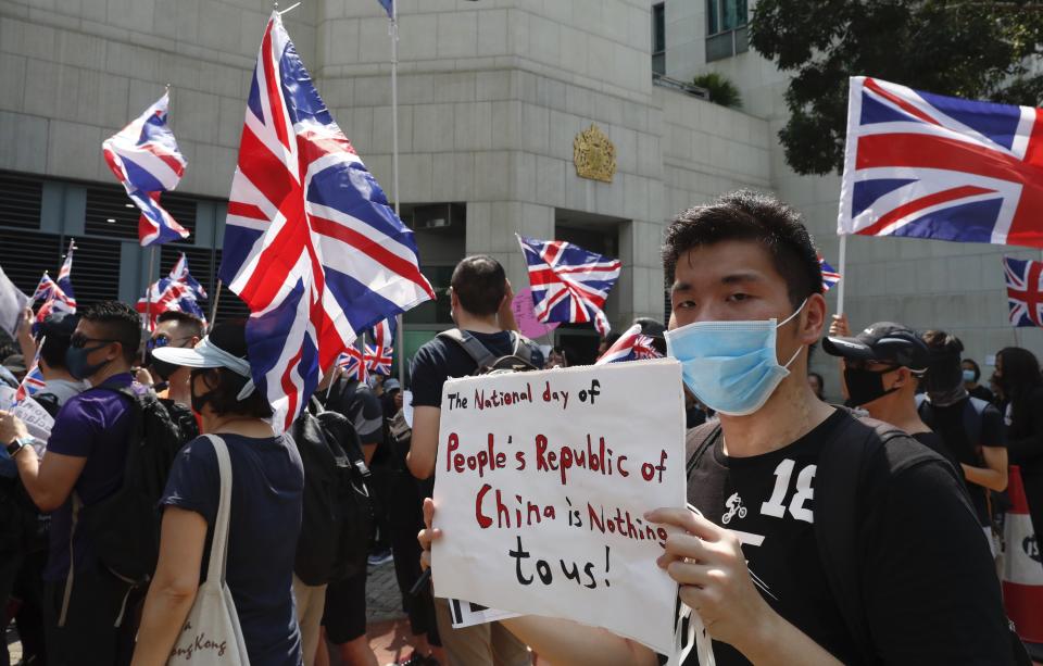 A man holds a placard as a group of Hong Kong residents waving U.K. flags demonstrate requesting right to British residency, Tuesday, Oct. 1, 2019, outside the British embassy in Hong Kong while the celebration of the People's Republic's 70th anniversary is taking place in Beijing. Police used pepper spray to break up a brief scuffle Tuesday between Beijing supporters and a small group of pro-democracy protesters who were marching in Hong Kong on the 70th anniversary of the founding of Communist China. (AP Photo/Gemunu Amarasinghe)