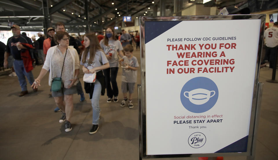 People make their way into Truist Park as they pass signage thanking fans for wearing a face mask per CDC guidelines prior to the baseball game between the Atlanta Braves and the Philadelphia Phillies on Saturday, May 8, 2021, in Atlanta. The Braves have opened the park to full attendance on the weekend for the first time in a year. (AP Photo/Ben Margot)