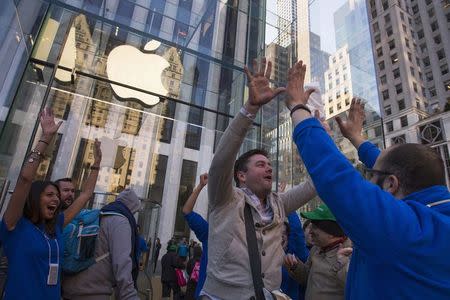 Local resident Andreas Gibson high-fives employees after being the first to exit the Fifth Avenue store after purchasing an iPhone 6 on the first day of sales in Manhattan, New York September 19, 2014. REUTERS/Adrees Latif