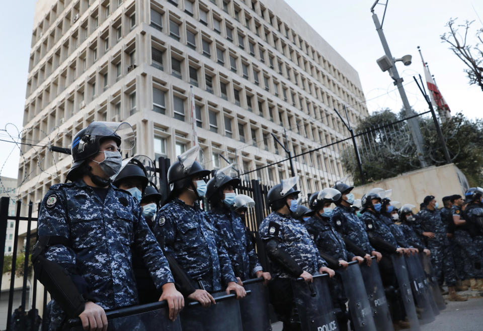 Lebanese riot police wear masks to help curb the spread of the coronavirus, as they stand guard in front the central bank building, where the anti-government protesters protest against the Lebanese central bank's governor Riad Salameh and against the deepening financial crisis, in Beirut, Lebanon, Thursday, April 23, 2020. (AP Photo/Hussein Malla)