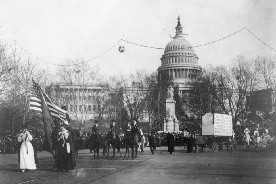 In this circa 1913 photo made available by the Library of Congress, demonstrators march in a women's suffrage parade near the Capitol building in Washington. A horse and cart pulls a sign which reads, "We demand an amendment to the constitution of the United States enfranchising the women of this country." (Harris & Ewing/Library of Congress via AP)