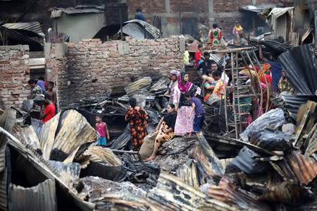 Slum dwellers are seen gather near their shelters after fire burnt them out in Dhaka