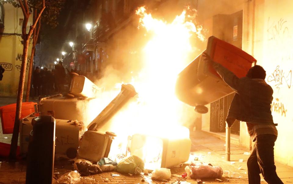 Varios contenedores incendiados en una de las calles de Lavapiés, muy cerca de donde murió el mantero (EFE).