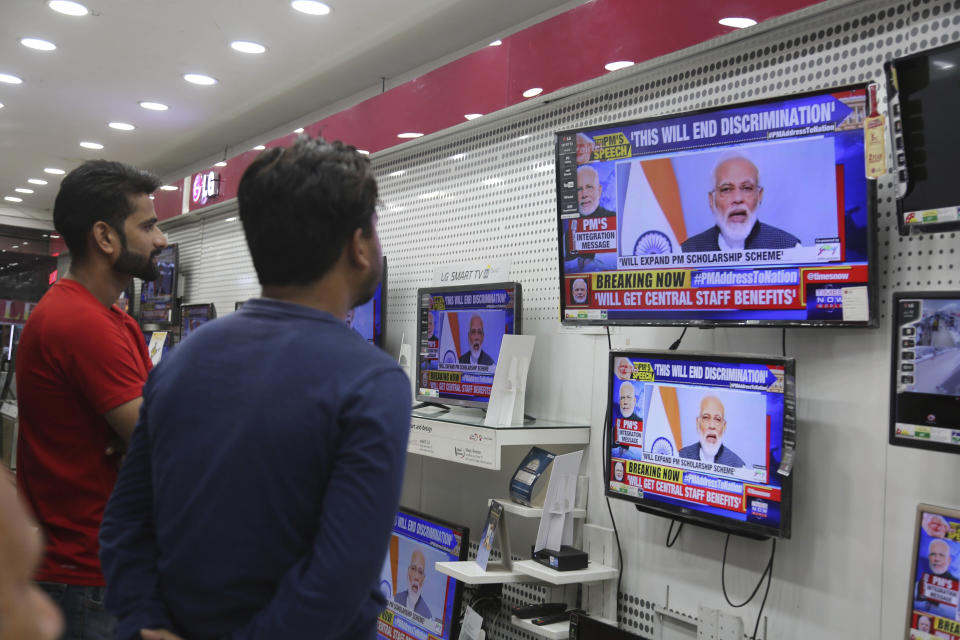 FILE - In this Thursday, Aug. 8, 2019, file photo, Indians at an electronics store in Jammu, India watch Prime Minister Narendra Modi address the nation on Kashmir in a televised speech. Modi’s Hindu nationalist government last week revoked an article in India’s constitution dating from shortly after independence from British rule, arguing that Kashmir’s special status had cultivated a sense of separatism that was exploited by India’s nuclear rival Pakistan, and choked development. (AP Photo/Channi Anand, File)