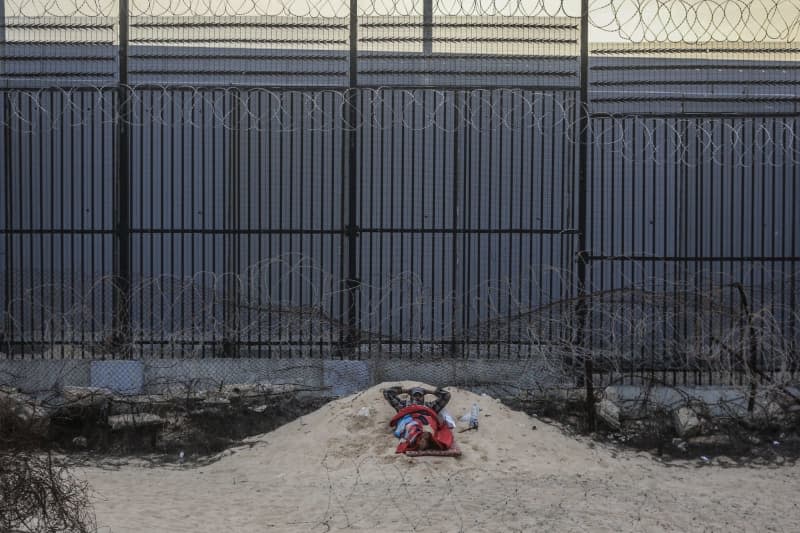 A displaced Palestinian man sleeps near the wall separating Egypt and the Gaza Strip. Mohammed Talatene/dpa