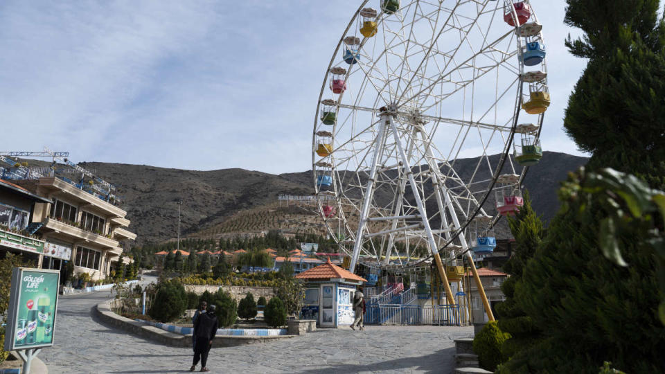This photograph taken on November 9, 2022, shows Taliban guards standing next to a ferry wheel ride at the Habibullah Zazai Park on the outskirts of Kabul. - The Taliban have banned Afghan women from entering the capital's public parks and funfairs, just months after ordering access to be segregated by gender. (Photo by Wakil KOHSAR / AFP)