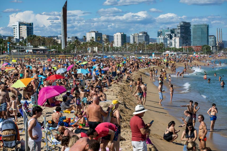 People enjoy the warm weather on the beach in Barcelona, Spain: AP