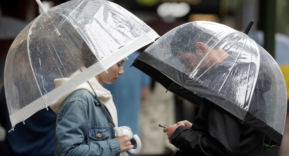 A couple shelter under an umbrellas as rain falls in Sydney. Source: AAP