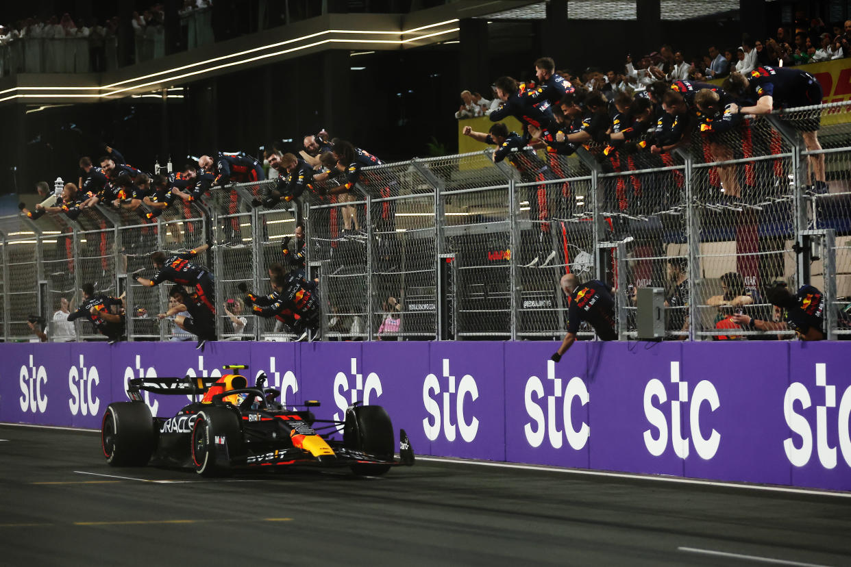 JEDDAH, SAUDI ARABIA - MARCH 19: Race winner Sergio Perez of Mexico driving the (11) Oracle Red Bull Racing RB19 passes his team celebrating on the pitwall during the F1 Grand Prix of Saudi Arabia at Jeddah Corniche Circuit on March 19, 2023 in Jeddah, Saudi Arabia. (Photo by Lars Baron/Getty Images)