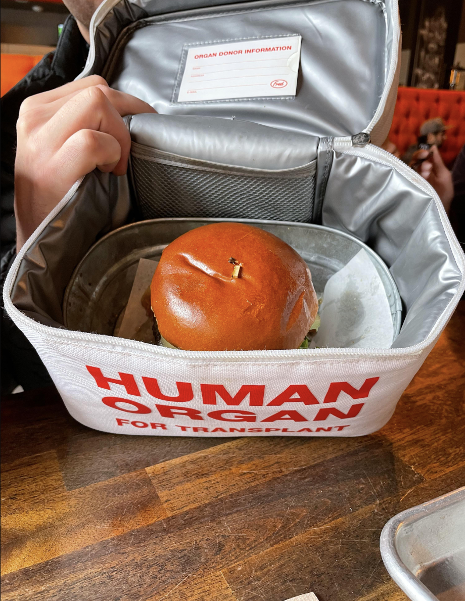 A burger served inside a bag that says "human organ for transplant"